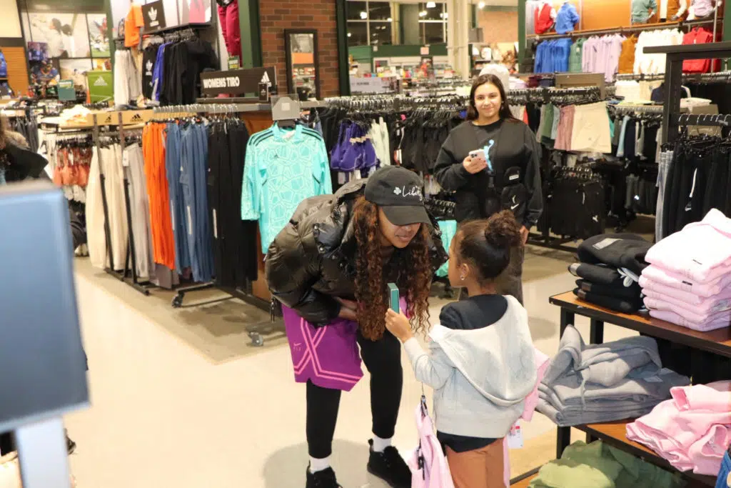 DiDi Richards talks to a child at a holiday event with DICK'S Sporting Goods